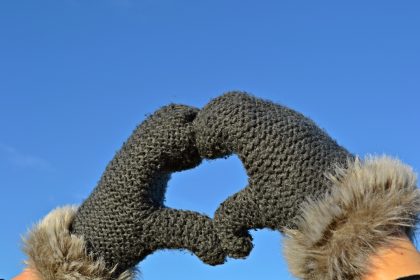 Mittened hands make heart shape with thumbs